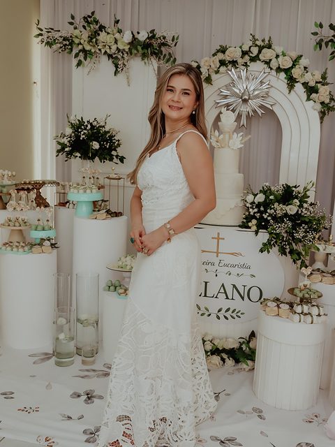 Cliente veste vestido longo branco com aplicações em renda, em uma celebração.