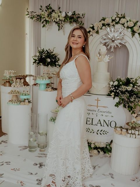 Vestido longo branco com barra em renda vazada, visto de corpo inteiro.